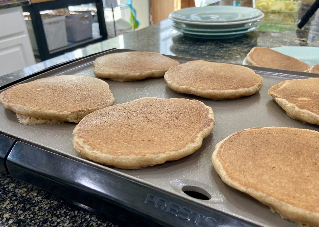 Overnight sourdough pancakes cooking on a griddle