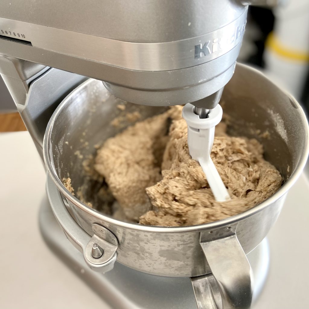 A stand mixer slowly mixing ingredients into a shaggy dough 