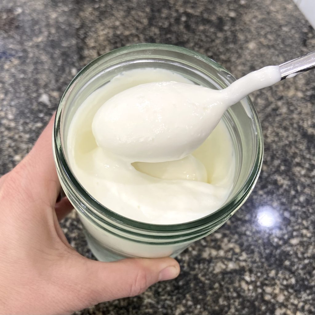 Yogurt in a jar, being scooped up by a spoon
