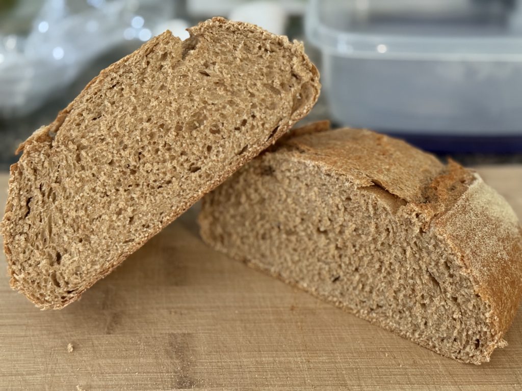 Einkorn Spelt Bread cut in half, resting on a cutting board.