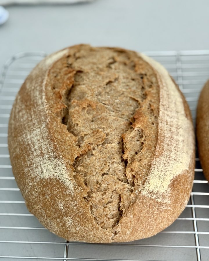 Loaf of einkorn spelt bread resting on a cooling rack