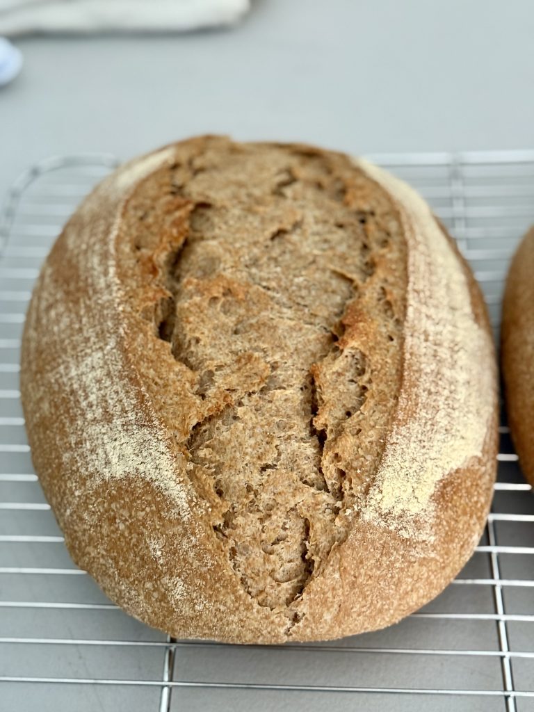 Loaf of einkorn spelt bread resting on a cooling rack