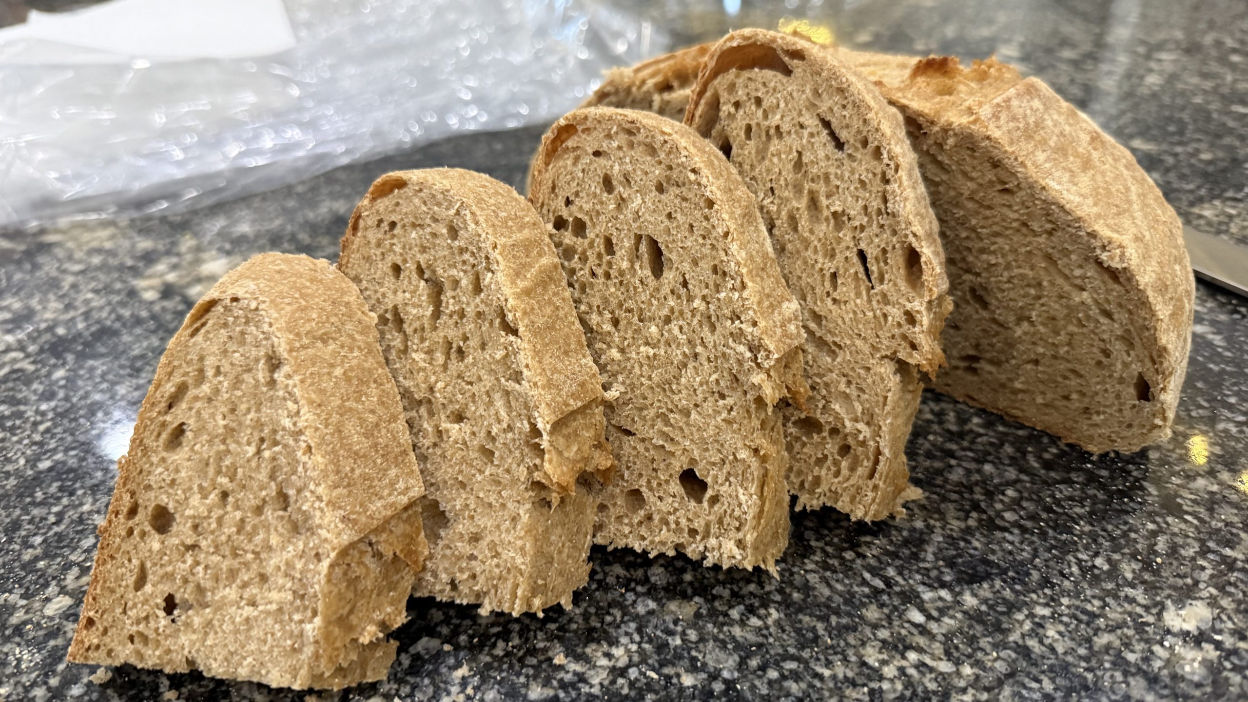 There are flour slices of sourdough sandwich bread laid artfully on a counter to display their crumb.