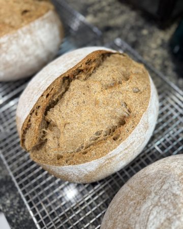 A loaf of bread resting on a cooling rack.