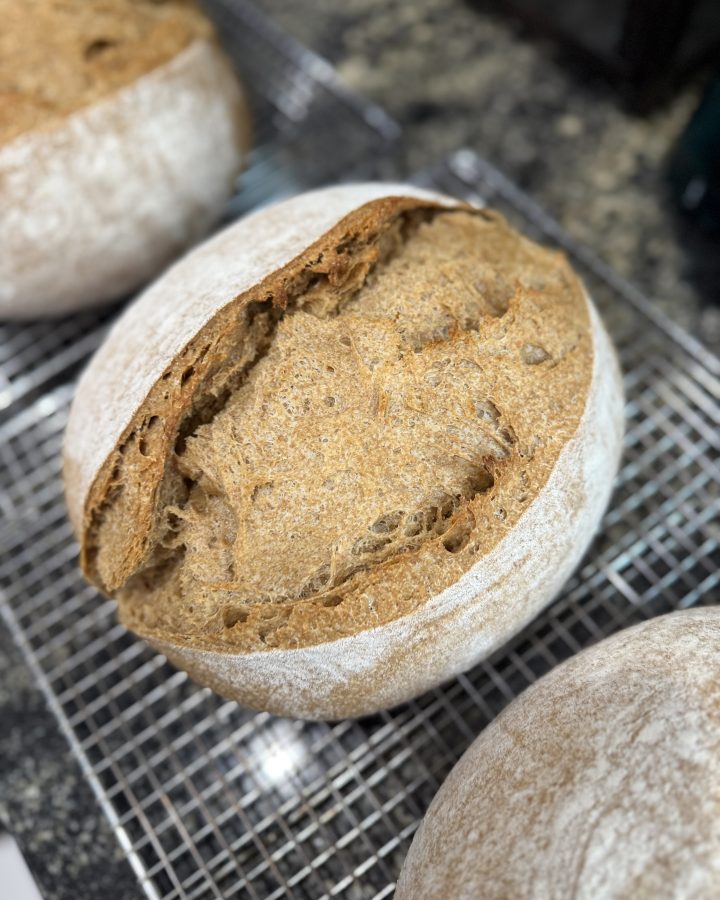 A loaf of bread resting on a cooling rack.