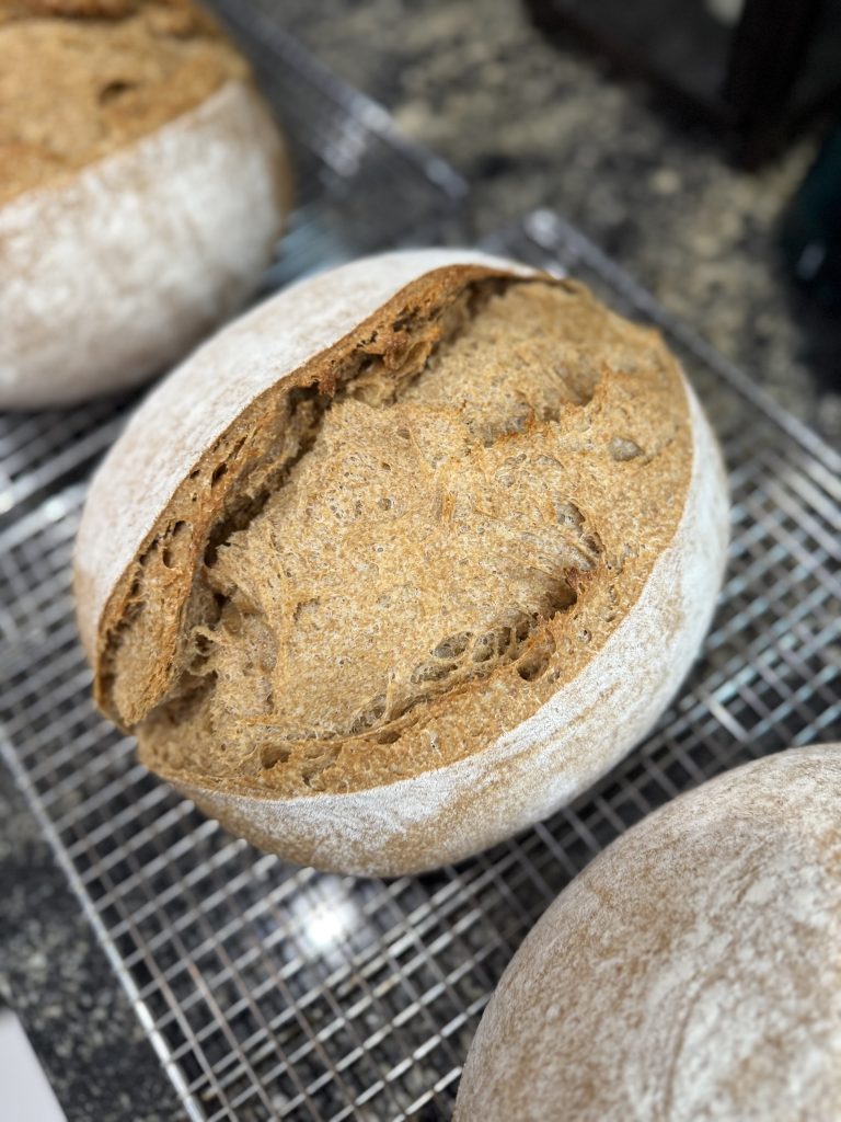 A loaf of bread resting on a  cooling rack.